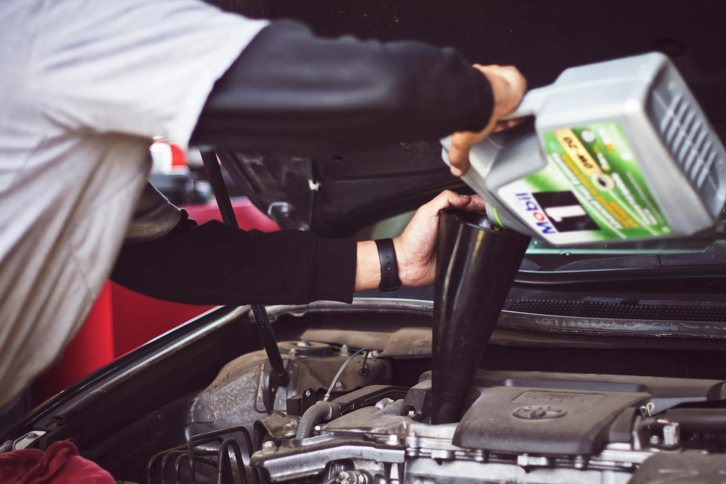 Man adding motor oil to a car engine